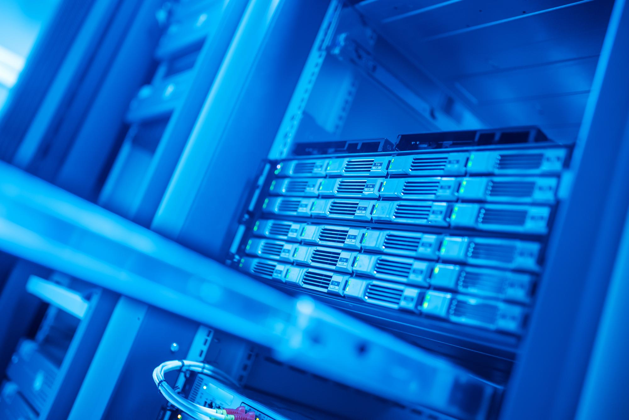 A close-up view of a server rack in a data center reveals multiple server units with visible front panels. The image boasts a blue hue, enhancing the sleek, modern design of the equipment, while proxy server addresses remain intricately managed within this digital hub. | BeTechIT