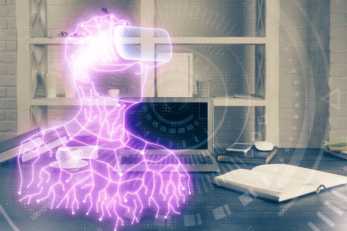 A glowing purple digital figure wearing virtual reality goggles appears superimposed over a modern office desk with a laptop, notebook, phone, and coffee cup, symbolizing technology and virtual reality integration. | Betechit.com