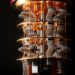 A close-up view of a quantum computer’s intricate interior, showing gold and silver wiring, coils, and circular layers against a black background. | Betechit.com